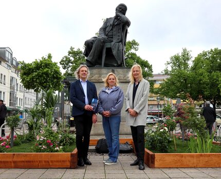 Dr. Thomas Synofzik (Leiter Robert-Schumann-Haus Zwickau), Annett-Dorothee Reiher (Floristin und Inh. Blumen Gellrich, Zwickau) und Kulturamtsleiterin Dr. Bianca Dommes bei der Präsentation der Bepflanzung des Schumann-Denkmals, das in diesem Jahr neben Robert Schumann ebenfalls am 8. Juni Geburtstag feiert.