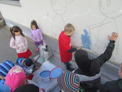 Graffitikünstler und Kids gestalten Kita-Hauswand