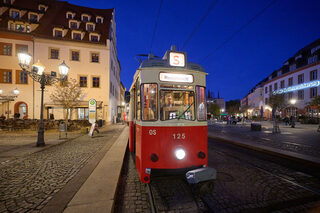 Eine historische rot-weiße Straßenbahn mit der Zielanzeige „Museumsnacht“ steht bei Dunkelheit in einer beleuchteten Straße.
